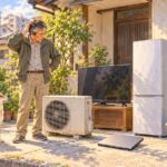 エアコンの室外機、テレビ、冷蔵庫、パソコン、原付を前に困る男性