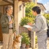 玄関先でリフォームの営業を、手を上げてやんわり断る男性と犬