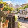 家電を積んだ軽トラックに、門の内側から断る男性と犬