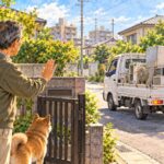 家電を積んだ軽トラックに、門の内側から断る男性と犬